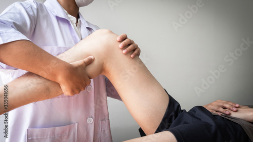 Therapist treating test the strength of the leg muscles of male patient.