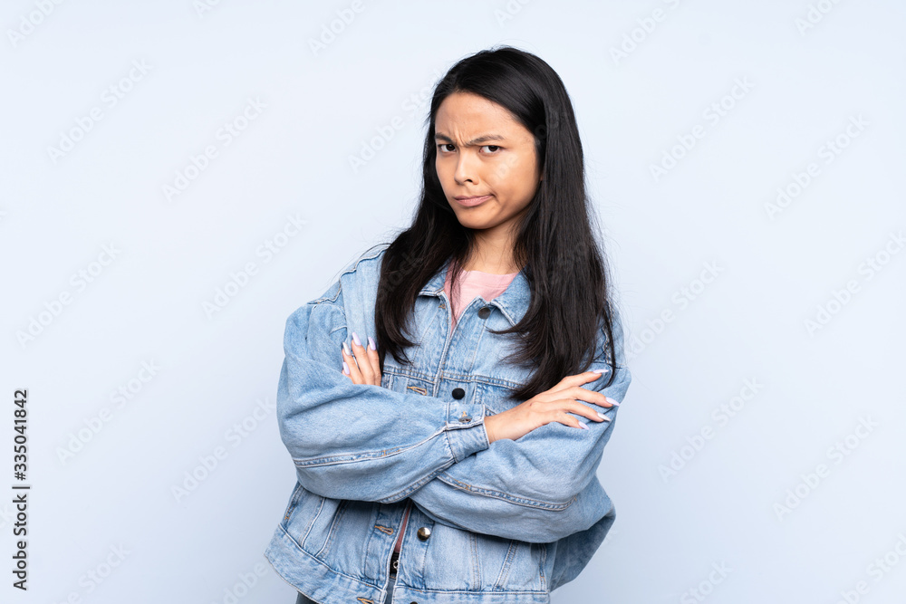 Teenager Chinese woman isolated on blue background feeling upset Teenager Chinese woman isolated on blue background feeling upset