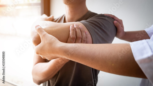 Obraz na płótnie Therapist treating a male injured by rotator cuff stretching method