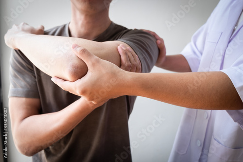 Therapist treating a male injured by rotator cuff stretching method.
