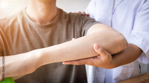 Therapist treating a male injured by rotator cuff stretching method.