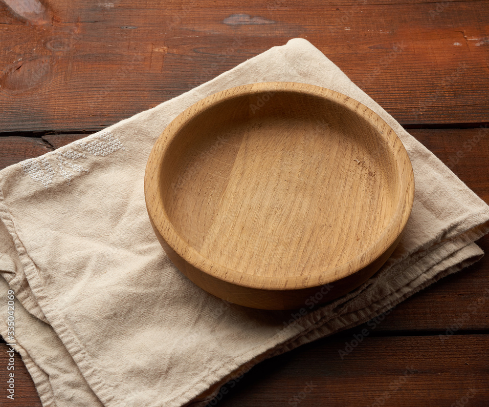 empty round brown plate standing on a gray linen napkin,