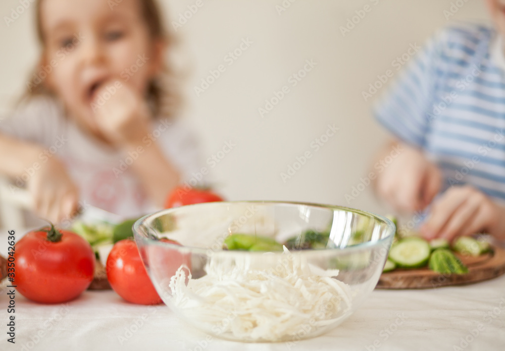 Happy children prepares vegetables for salad in home kitchen. Healthy eating. Happy children prepares vegetables for salad in home kitchen. Healthy eating.