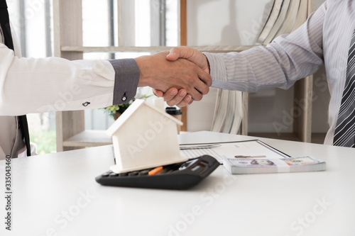 Agent and customer are shaking hand after finishing an advice for taking the house insurance