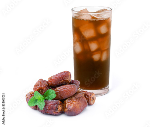 Glass of ice date tea and pile of dates palm fruit with green mint leaf  isolated on white background. Healthy drink concept. photo