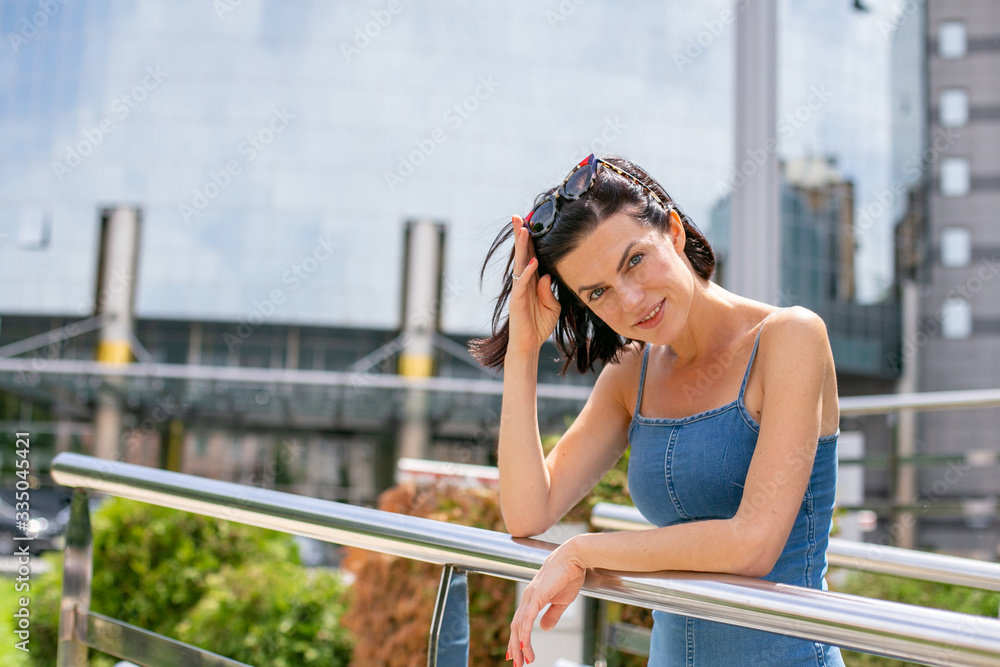 horizontal portrait of a beautiful brunette with short hair on a background of modern buildings