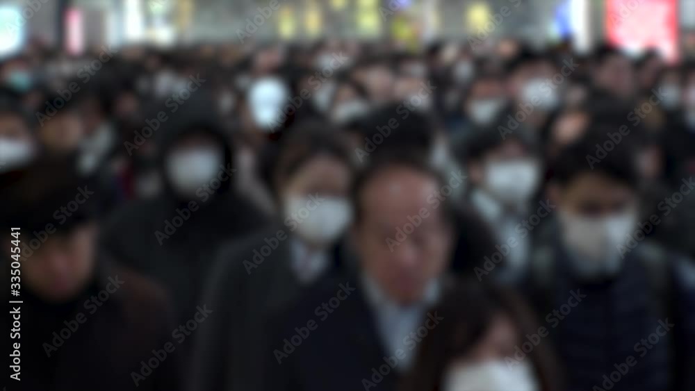 TOKYO, JAPAN - MARCH 2020 : Crowd of people walking at morning rush hour. Commuters going to work. People wearing mask to protect from Coronavirus(COVID-19). Blurred slow motion shot. TOKYO, JAPAN - MARCH 2020 : Crowd of people walking at morning rush hour. Commuters going to work. People wearing mask to protect from Coronavirus(COVID-19). Blurred slow motion shot.