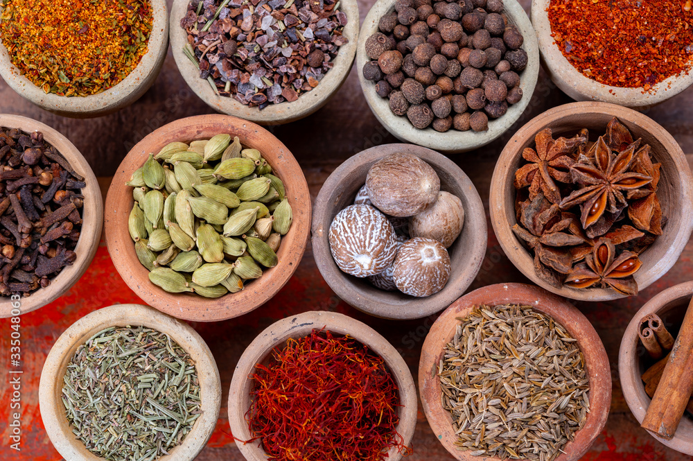 Indian spices collection, dried colorful condiment, nuts, pods and seeds and another spices in clay bowls Indian spices collection, dried colorful condiment, nuts, pods and seeds and another spices in clay bowls