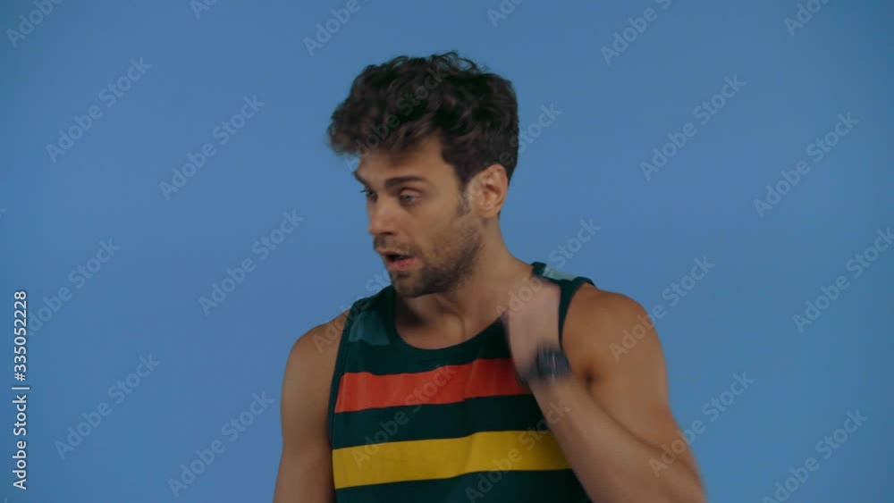 Man suffering from heat and using electric fan isolated on blue