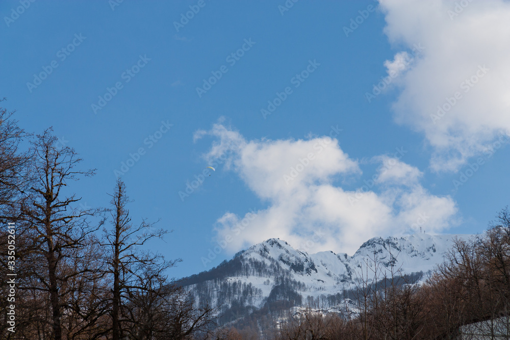 Peaks of snow-capped mountains against the blue sky with clouds