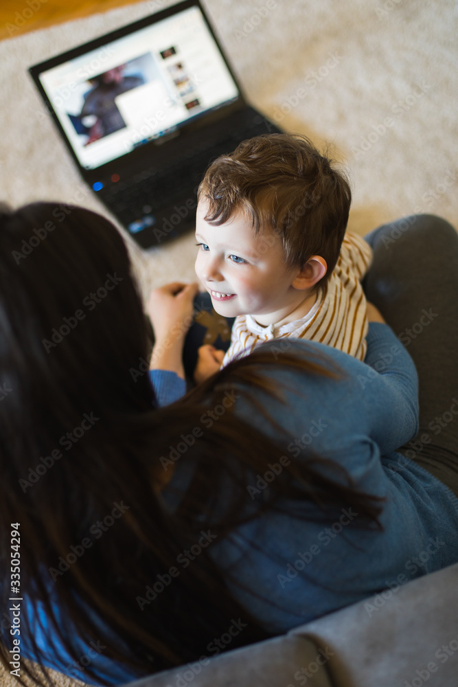 Cute child looking to his mother while the are watching digital entertainment content on laptop. Cute child looking to his mother while the are watching digital entertainment content on laptop.