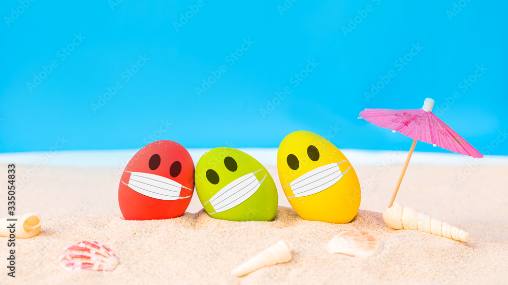 Obraz premium colorful eggs wear fabric mask on white sand beach over cloudy sky background, image for happy Easter or Happy weekend concept.
