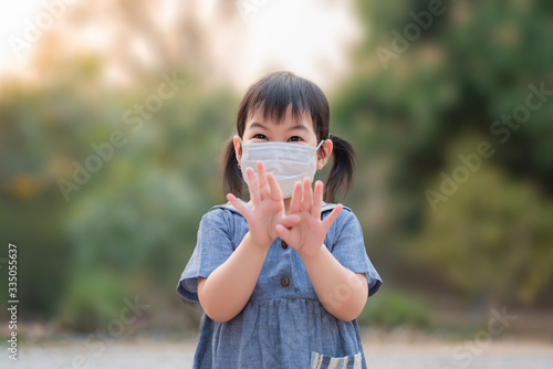 Cute Asian girls wear masks to protect against covid-19 viruses and Pm2.5 air pollution, and show a stop hand gesture to stop the covid-19 virus outbreak. Coronavirus and Air pollution PM2.5 concept.