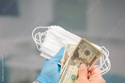 close up of doctor's hand in medical gloves with set of medical face masks and a hand with money 