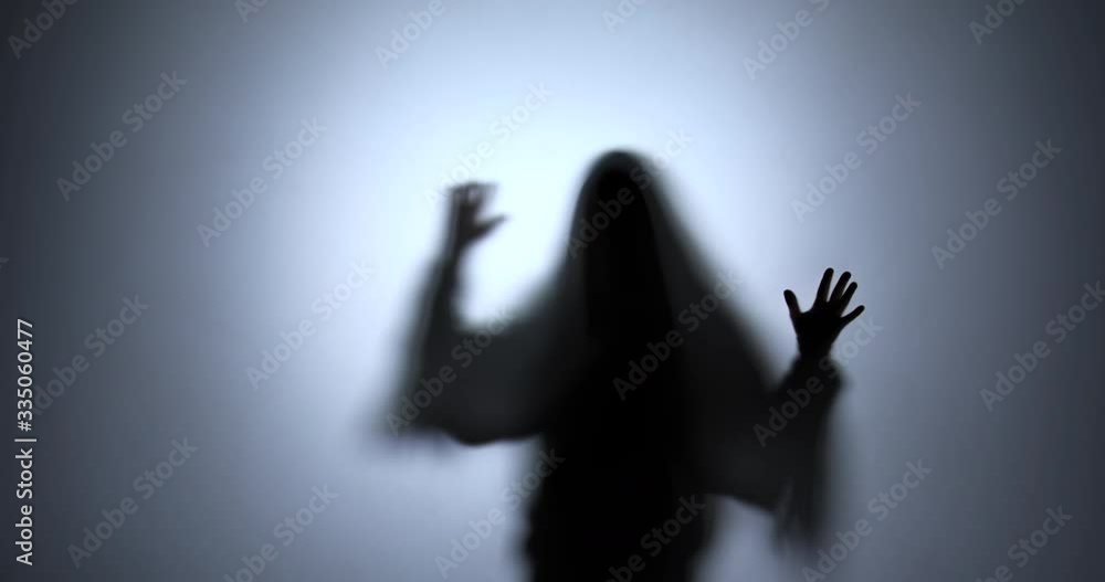 The black silhouette of a ghost frighteningly moves his hands across the screen