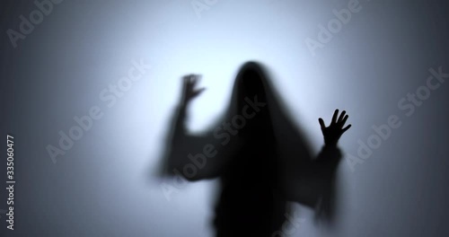 The black silhouette of a ghost frighteningly moves his hands across the screen