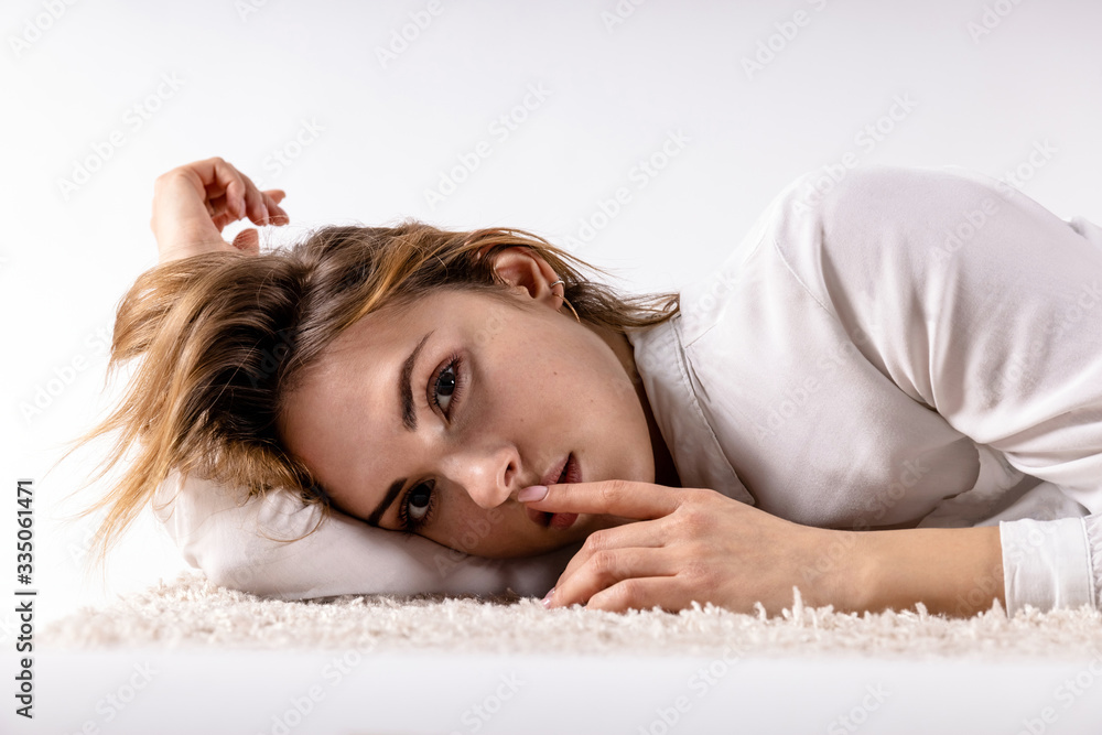 Fototapeta premium young girl lies on her side on her hand on the floor on a white background