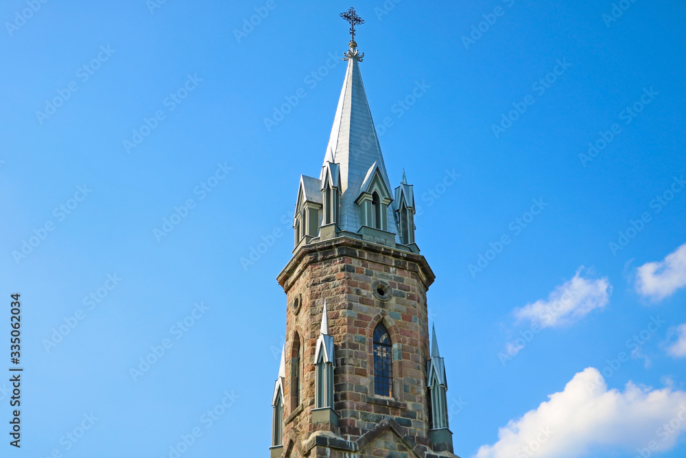 Obraz premium The spire of the old church against the blue sky.