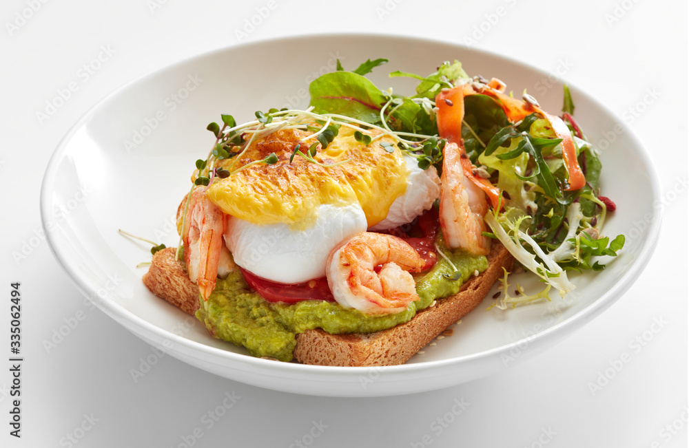 eggs benedict with hollandaise, shrimps and guacamole on toast with salad eggs benedict with hollandaise, shrimps and guacamole on toast with salad