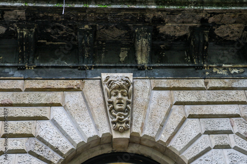 A sculpture of Medusa's head with snakes adorns a keystone above a window arch in an old building in Budapest, Hungary.