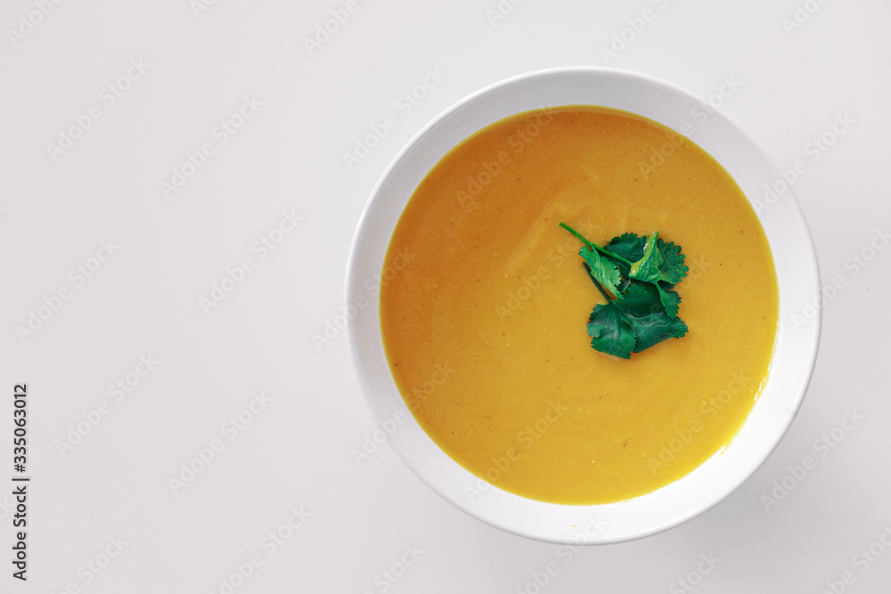 Homemade pumpkin soup with greens on a white background