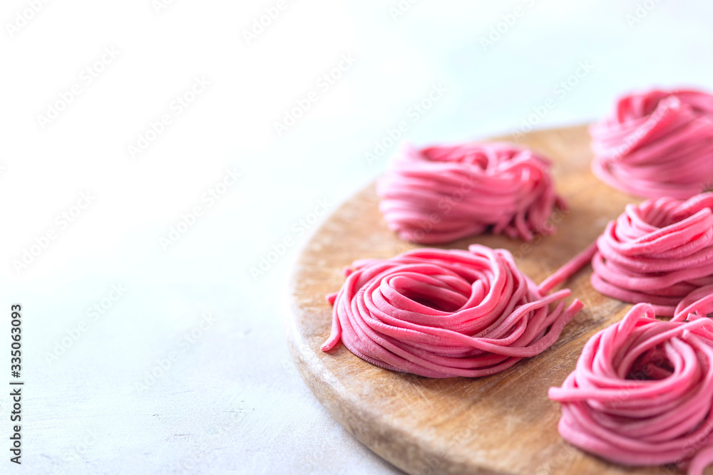 Fresh Hand made beetroot pasta on wooden cutting board. Raw purple spaghetti, fettuccine. Fresh Hand made beetroot pasta on wooden cutting board. Raw purple spaghetti, fettuccine.