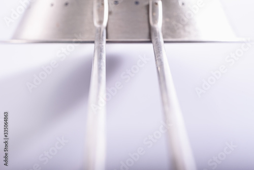 Detail, with unfocused background, of a metallic steel kitchen accessory in white light background.