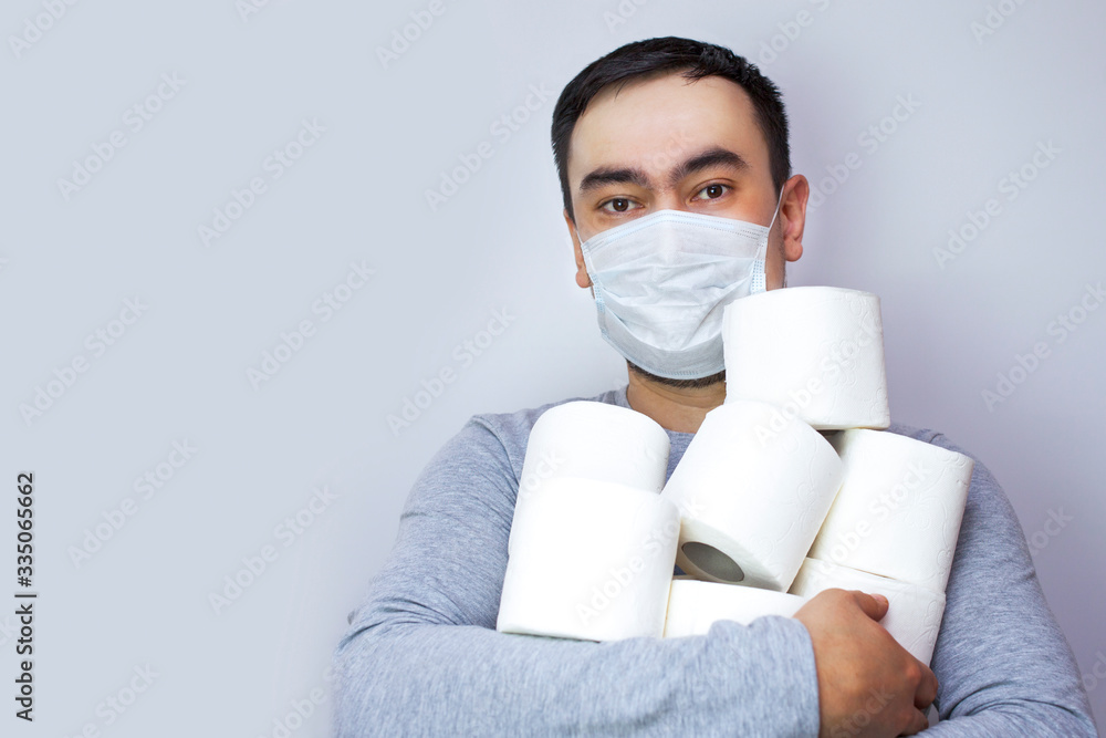 A man in a medical mask is holding a large amount of toilet paper A man in a medical mask is holding a large amount of toilet paper