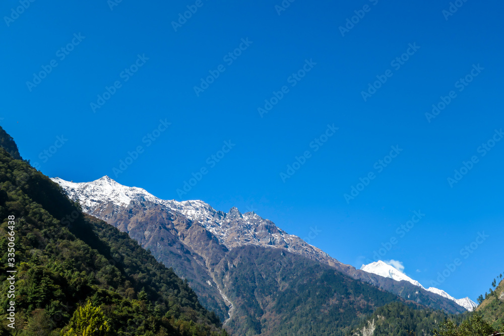View on Himalayas, Annapurna Circuit Trek, Nepal. Early morning in the mountains. Lower parts of the mountains covered in shadow, high snow caped mountains peaks catching the first beams of sunlight View on Himalayas, Annapurna Circuit Trek, Nepal. Early morning in the mountains. Lower parts of the mountains covered in shadow, high snow caped mountains peaks catching the first beams of sunlight