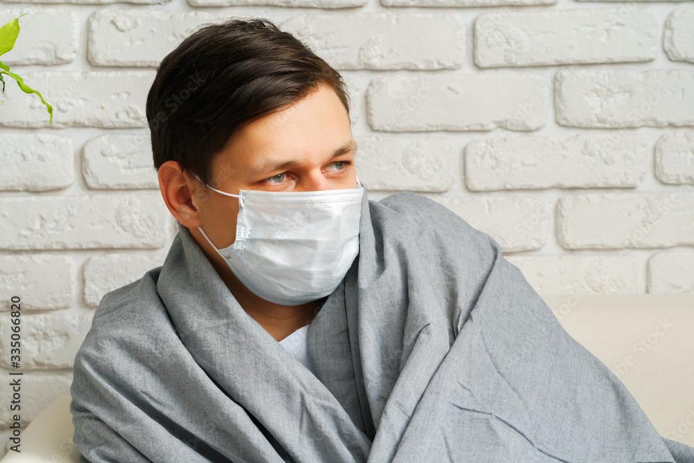 Caucasian man staying at home during Coronavirus / Covid-19 quarantine wearing medical mask