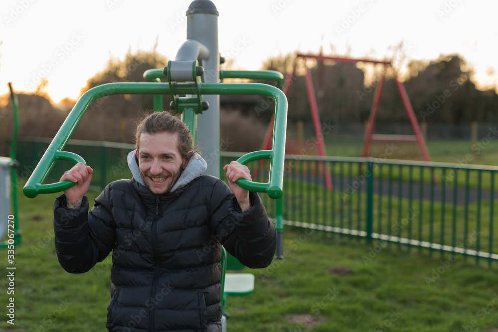 Obraz premium A young adult male using public exercise equipment in his local