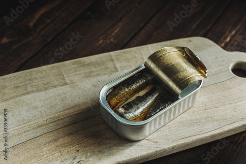 Opened can of sardines on a wooden cutting table