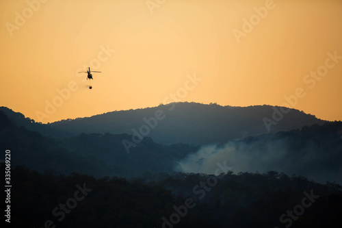 The helicopter is drawing water from the reservoir and will be watered to extinguish the burning forest in the mountains.
