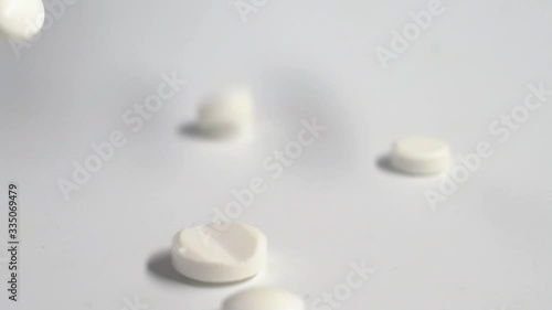 Huge number of white pills falling on white background  slow motion.Macro