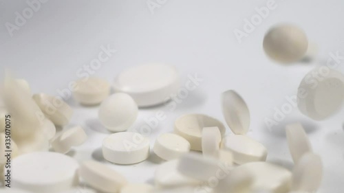 Huge number of white pills falling on white background  slow motion.Macro