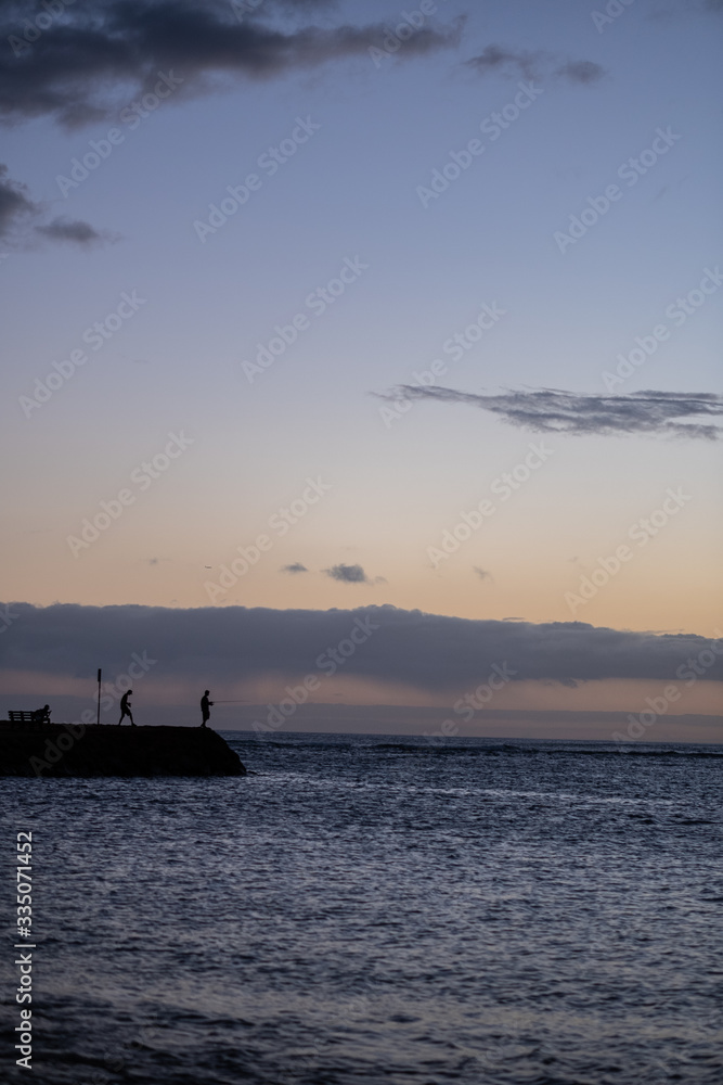 Man fishing during Sunset over pacific ocean silhouette, honolulu, HI, September 11, 2018