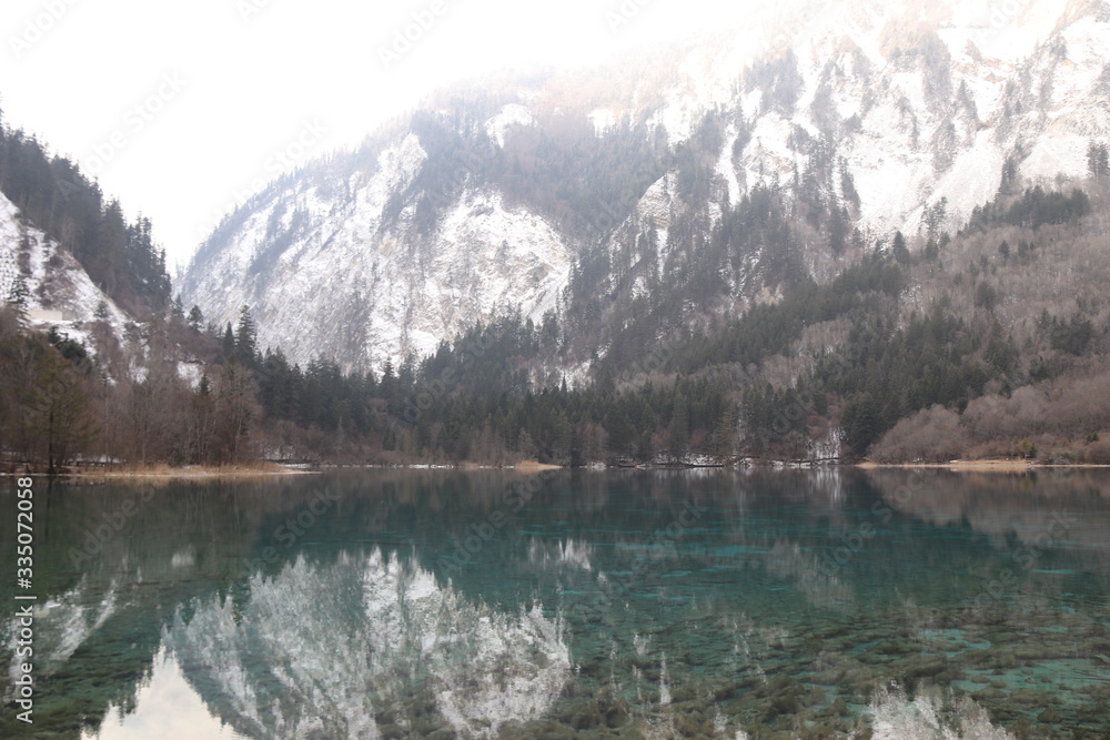 beautiful landscape of a lake in national park, Sichuan China with snow and reflection of the trees in the water