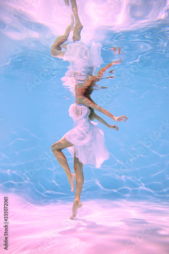 A woman underwater in a pool wrapped in cloth