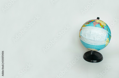 Earth globe is wearing a protective mask  as a symbol of the fact that all people of the entire planet are quarantined due to the epidemic and pandemic of Coronavirus. Copy space  banner or template.