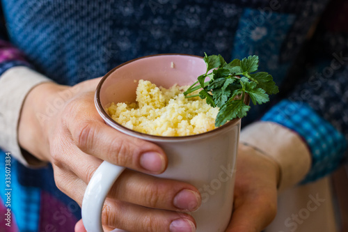 Cooked couscous durum wheat grain porridge in cup. Crushed semolina millet. Vegan healthy food.