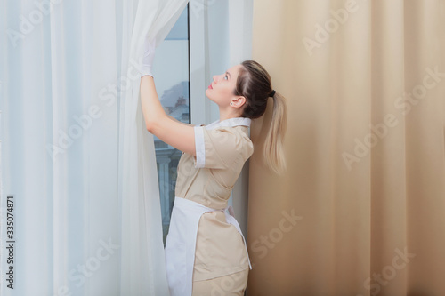 The maid airs and cleans the hotel room. Copy of the space.