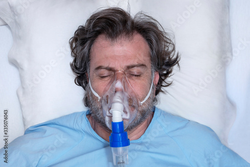 Aerial portrait of an elderly person, with oxygen mask, in a hospital bed