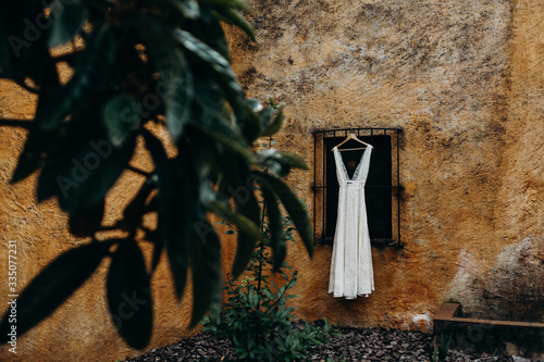 Vestido de novia colgado de una ventana con un árbol