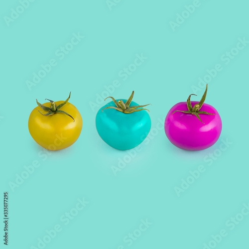 Three tomatos with strange color on blue background. Concept of GM food. 
