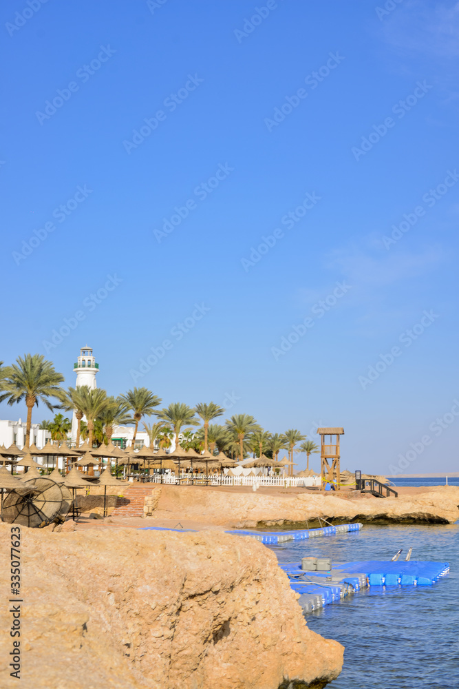 Buildings of the luxury hotel and palm alley on egyptian beach, lighthouse. Red Sea. Egypt. Filtered image:cross processed lomo effect.
