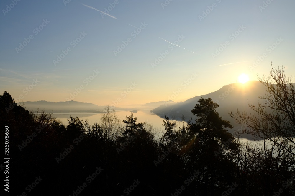 Beautiful sunrise view of the WortherSee lake from the Ferienhotel WortherSee located on the northern shores of the lake. It is the largest lake in Carinthia, Austria. Beautiful sunrise view of the WortherSee lake from the Ferienhotel WortherSee located on the northern shores of the lake. It is the largest lake in Carinthia, Austria.