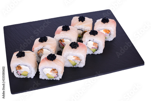 Traditional fresh japanese sushi rolls on a black stone Dragon Izumi on a white background. Roll ingredients: izumai perch, philadelphia cheese, surimi, tomago omelette, avocado, black tobik, nori, ri photo