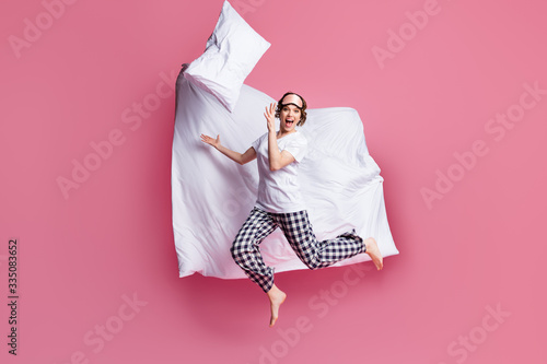 Full size photo of funny lady jump high throw pillow up blanket flight rejoicing slumber party wear sleep mask white t-shirt plaid pajama pants barefoot isolated pink color background