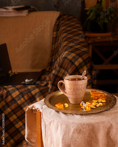 Cup of tea, sweets on vinage tray on stool and thinks for remote work on background. Stay at home concept, freelance, business, bloger, writer or remainig at home because of pandemia. Vertical photo