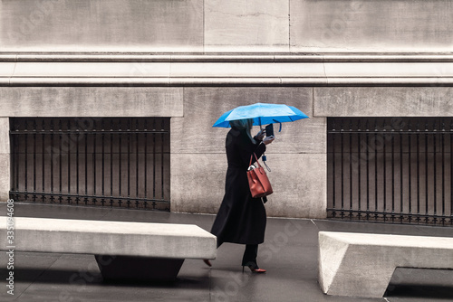women with a ​blue umbrella in downtown new york